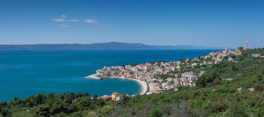 Панорамный вид на Игране, Хорватия, с прибрежным поселком, набережной и окружающими горами