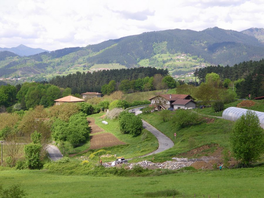Сельский ландшафт с фермерскими домами, деревьями и лугами в Игorre, Бискайя
